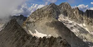 Mountainous Panoramic View Prints: A panoramic view of a rugged mountain range partially covered by clouds