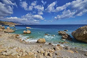 Pebble Beach Greece Prints: Pebble beach with large rocks and gentle waves under a cloudy sky