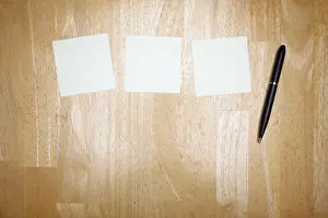 Empty Desk Setup Prints: Pen and post it notes pad against a wood background