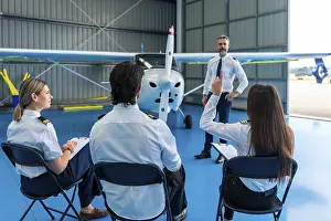 Pilot Instructor Training Prints: Pilot instructor explaining aviation concepts to students in a hangar