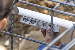 Deserted Construction Area Prints: Plumber using level while installing PVC pipe at construction site