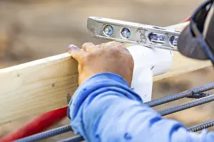 Construction Site Work Prints: Plumber using level while installing PVC pipe at construction site