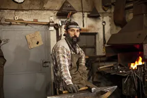 Blacksmith At Work Prints: The portrait of bearded blacksmith preparing to work in his workshop