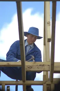 Young Construction Worker Prints: Apprentice builder using hammer on building site