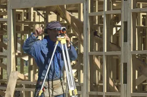 Young Construction Worker Prints: Builder with dumpy level giving instructions