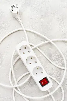 Office Work Station Setup Prints: Power strip with multiple sockets and a switch in a cluttered setup on a textured surface during daytime