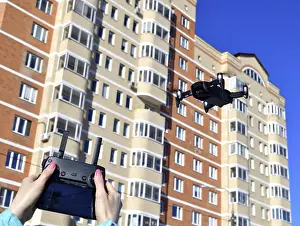 Aviation Technology Images Prints: Quadrocopter flies in the sky and hands with a control panel