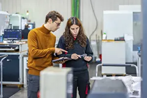 Industrial Building Inspection Prints: Quality control of two engineers standing and talking while using tablet in a cnc factory