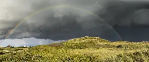 Prismatic Colors In Nature Prints: Rainbow with dramatic rain clouds over dune landscape