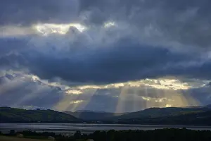 Mountainous European Landscapes Prints: Rays of light break through dramatic clouds over a lake and mountain landscape