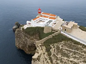 Portuguese Coastal Scene Prints: A red lighthouse on a cliff above the ocean