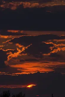 Deserted Evening Atmosphere Prints: Red sun behind clouds in the evening sky