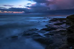 Cloudy Atmospheric Landscape Prints: Rocky coast with dramatic dark clouds at sunset