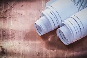 Deserted Construction Site Prints: Rolled blueprints on brazen background construction concept