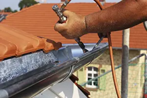 Residential Building Construction Site Prints: Roofer doing tinsmith work on a gutter