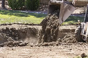 Real Estate Market Development Prints: Small bulldozer digging in yard for pool installation