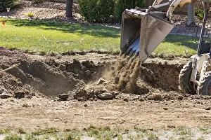 Agricultural Machinery Use Prints: Small bulldozer digging in yard for pool installation