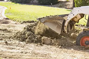 Agricultural Machinery Use Prints: Small bulldozer digging in yard for pool installation
