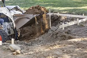 Agricultural Machinery Use Prints: Small bulldozer digging in yard for pool installation