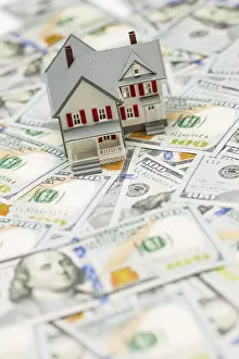 Residential Building Cost Prints: Small model house on layer of one hundred dollar bills