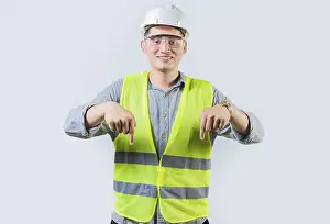 Construction Worker Portrait Prints: Smiling engineer pointing advertising down isolated