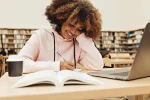 Office Work Desk Setup Prints: Smiling student writing in library