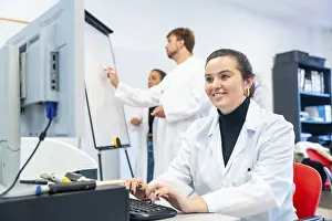 Young Scientist Prints: Smiling young scientist using computer in the office of a laboratory