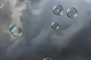 Iridescent Soap Bubbles Prints: Soap bubbles iridescent, floating in front of dark clouds