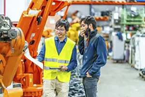Metal Fabrication Technology Prints: Software engineer explaining to controlling robotic welding process to welder in factory