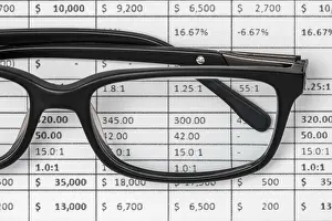 Analyzing Financial Data Prints: Detail of a spreadsheet and glasses on the table in the office