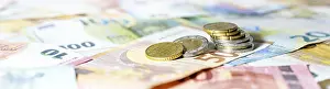 Euro Banknotes And Coins Prints: Stack of coins on euro banknotes as wide panoramic format