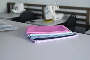 Colorful Fabrics Prints: A stack of colorful fabrics on a table in a sewing workshop