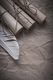 Deserted Table Setting Prints: Stack of vintage paper scrolls feather on crumpled wrapping sheet