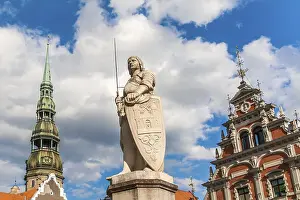 Prints of A statue of Riga's patron saint, St Roland, stands between the House of Blackheads and the Town Hall A statue of Riga's patron saint, St Roland Latvia Prints: Riga's St Roland Statue Print