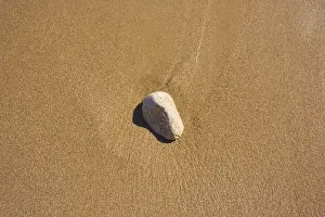 Empty Shoreline Spain Prints: Stone lying in the sand on a beach