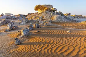 Deserted Omani Landscapes Prints: Striking cliffs surrounded by windswept sand structures