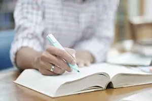 University Campus Life Prints: A student writes notes in a notebook while studying in a library
