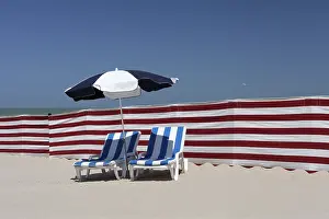 European Vacation Spots Prints: Two empty sun-beds behind a windbreak