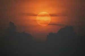 Atmospheric Evening Mood Prints: Sun disk through the clouds at sunset above the horizon