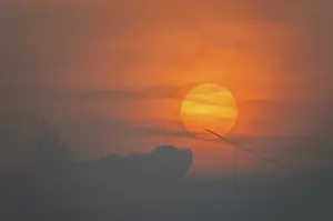 France Travel Photography Prints: Sun disk through the clouds at sunset above the horizon