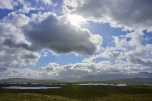 Deserted Lake In Scotland Prints: Sun rays break through dramatic clouds over a vast landscape with lakes