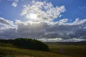 Scottish Highland Travel Photos Prints: Sunshine and clouds over a forest on a clear sky