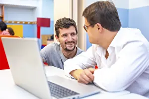 Young Adult With Disability Prints: Teacher talking to a man with down syndrome during computing class