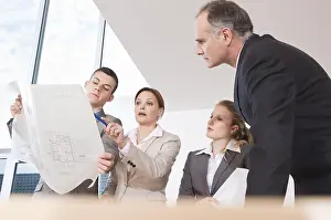 Workplace Collaboration Prints: Team of four architects discussing an construction plan