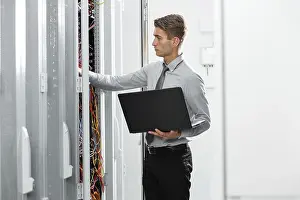 Healthcare Technology Prints: Technicians using laptop while analyzing server in server room