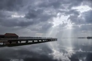 Tranquil Lake Scene Prints: A tranquil lake scene with a dock and dramatic clouds reflecting on the water's surface