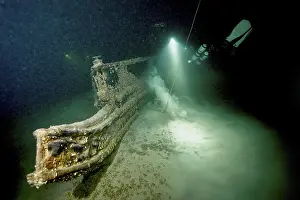 Lake Constance Dive Site Prints: Underwater image of a diver approaching a shipwreck with a light source
