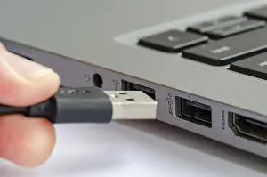 Cybercrime Prevention Tips Prints: USB being plugged into laptop highlighting risk of unauthorized data transfer or malware