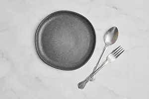 Empty Ceramic Plate Prints: Top view of empty ceramic plate and spoon with fork on marble background