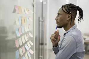 Businessman Thinking Prints: Side view man thinking office while looking sticky notes